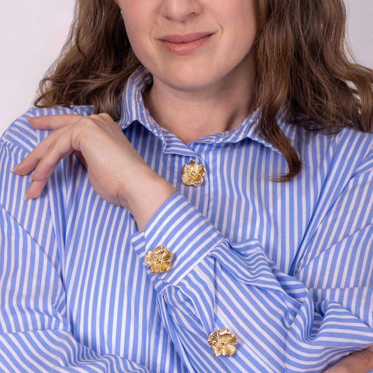 woman wearing a striped shirt with gold flower button covers
